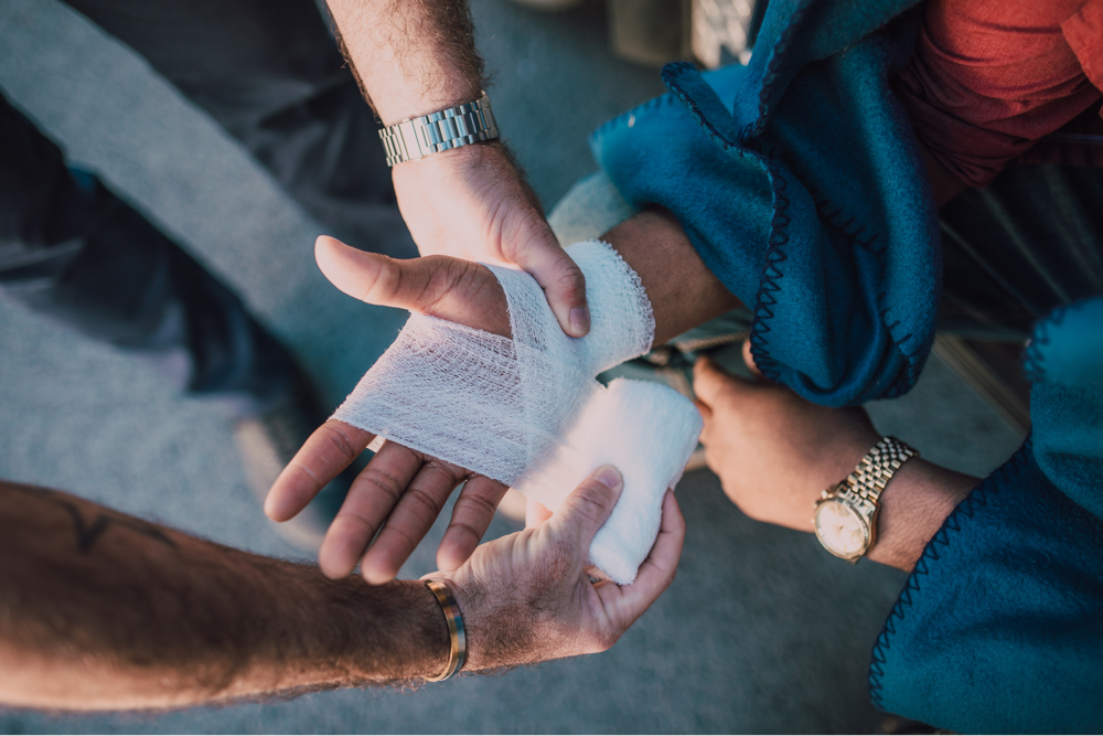 Close-up of a person receiving medical treatment for a hand injury with gauze bandage wrapping